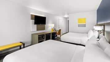 Une chambre d’hôtel avec deux lits, un bureau, une chaise, une télévision et une lampe.