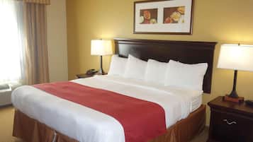 A hotel room with a large bed, two bedside tables with lamps, a framed picture on the wall, and a window with curtains.