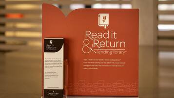 A promotional display for a Read it & Return Lending Library, featuring a book and a box with text about the library's services and partnerships.