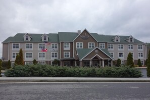 Un hotel grande con varios pisos, un cartel llamativo que dice 'Country Inn & Suites' y varias banderas a la vista.