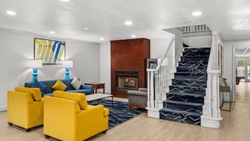 A modern living room with a sofa set, a fireplace, and a staircase.