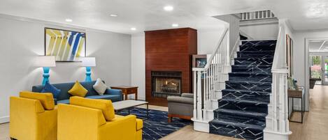 A modern living room with a sofa set, a fireplace, and a staircase.