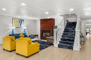 Una sala de estar moderna con un conjunto de sofás, una chimenea y una escalera.