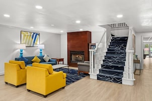 A modern living room with a sofa set, a fireplace, and a staircase.