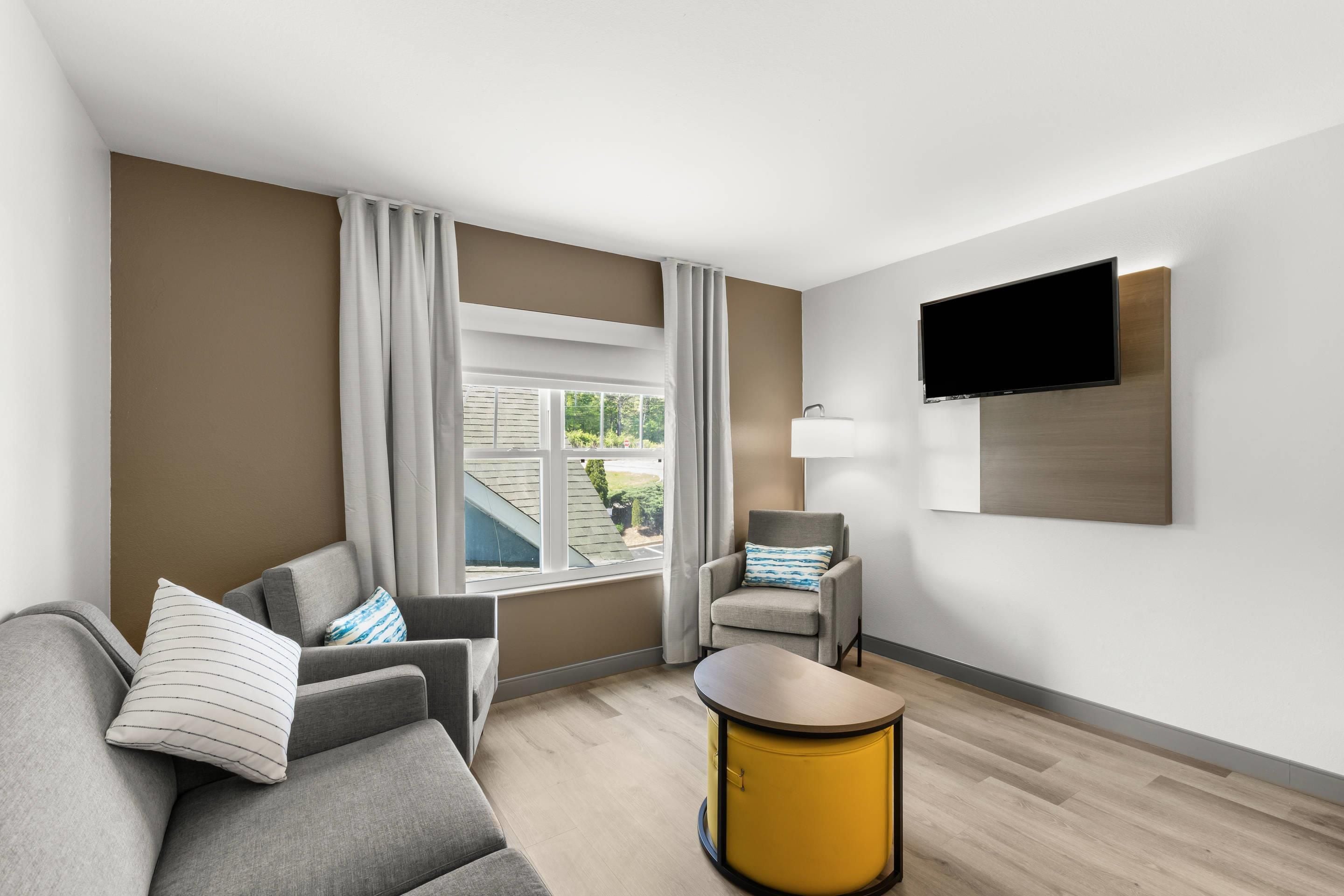 Ett modernt hotellrum med en soffa, en fåtölj och ett litet bord.