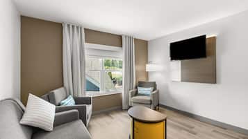 A modern hotel room with a sofa, armchair, and a small table.