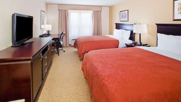 A hotel room with two beds, a TV, a desk, and a chair.
