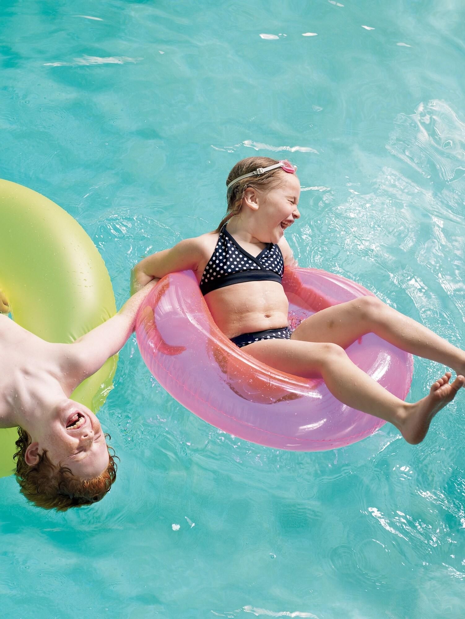 A person floating on a pink inflatable ring in a pool.