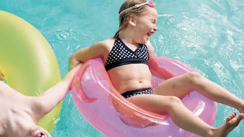 A person floating on a pink inflatable ring in a pool.