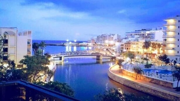 Un hôtel situé au bord de l’eau, avec un pont, une vue sur l’eau et des bâtiments illuminés.