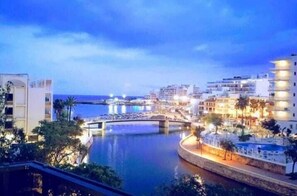 Un hotel frente al agua, con un puente, agua e edificios iluminados.