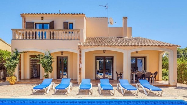 A two-story building with a swimming pool, sun loungers, and a covered patio area. - Villa Karen (Sa Rapita)