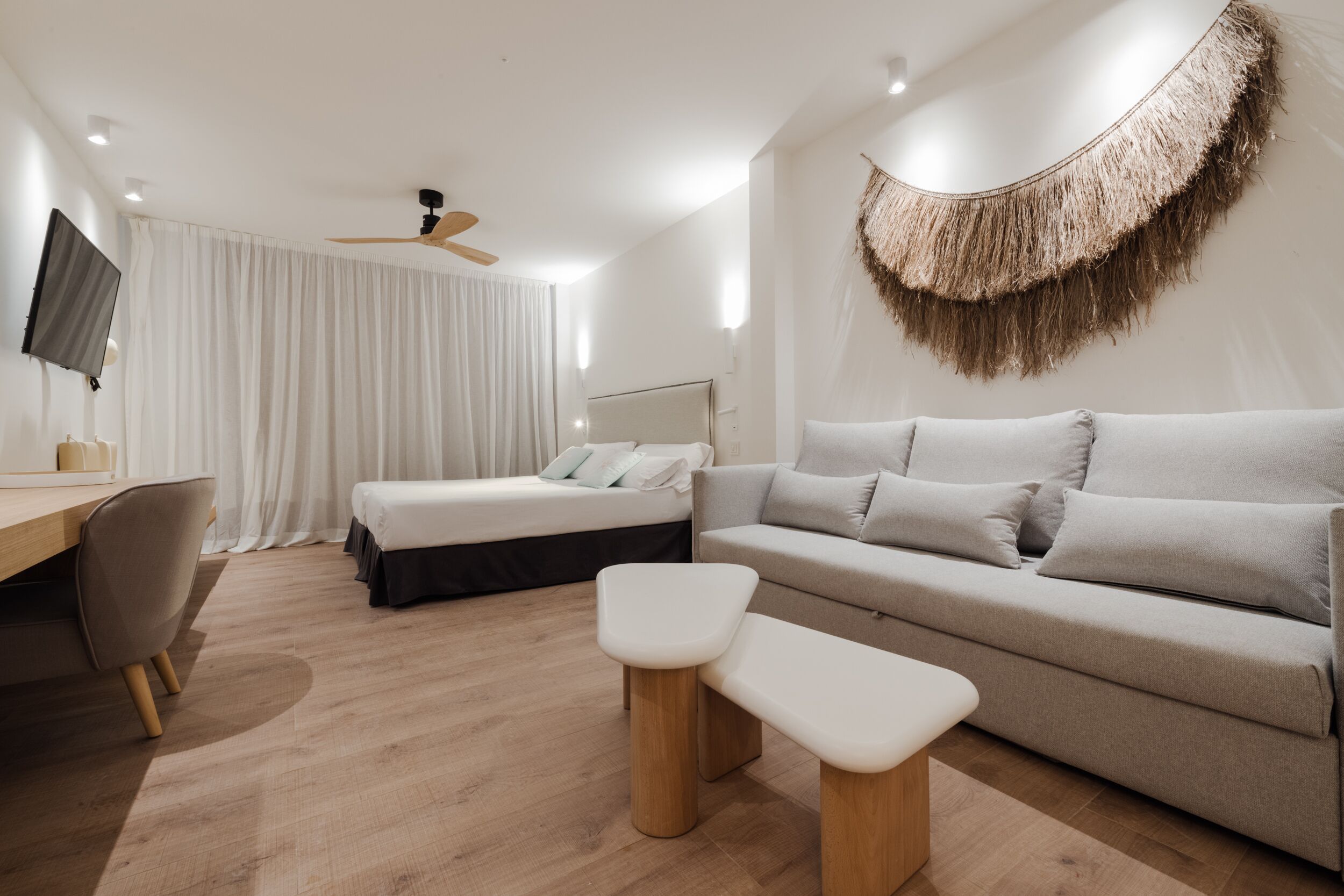 Ein modernes Hotelzimmer mit Bett, Sofa, Schreibtisch und Fernseher.