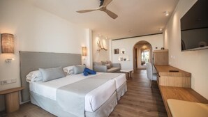 A modern hotel room with a large bed, a desk, a sofa, and a ceiling fan. - Blau Park (San Antonio)