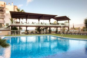 A swimming pool with lounge chairs and a covered seating area. - Blau Park (San Antonio)
