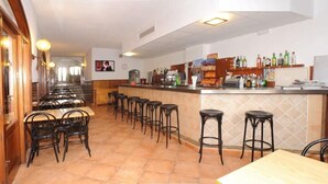 Een restaurant met een bar, meerdere tafels en stoelen en een betegelde vloer.