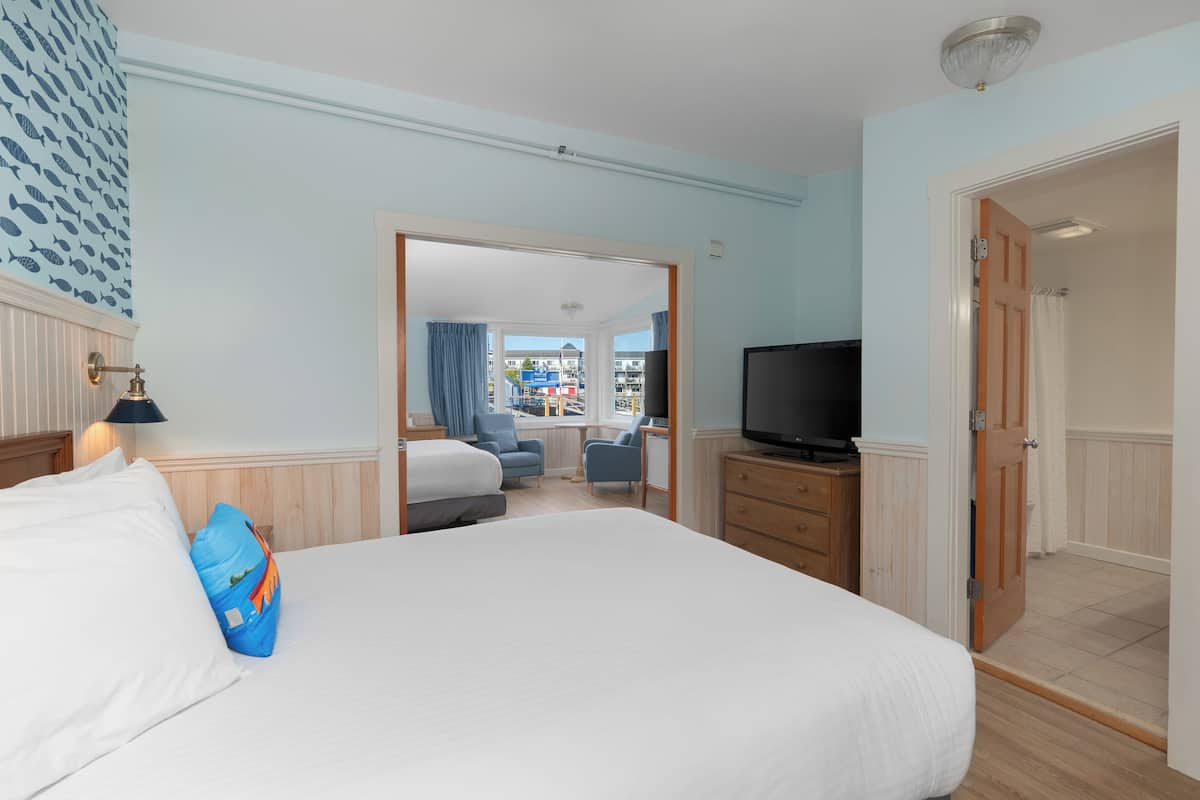 A hotel room with a large bed, a television, a desk, and a view of the outside.