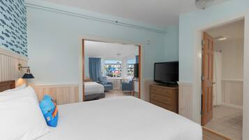 A hotel room with a large bed, a television, a desk, and a view of the outside.