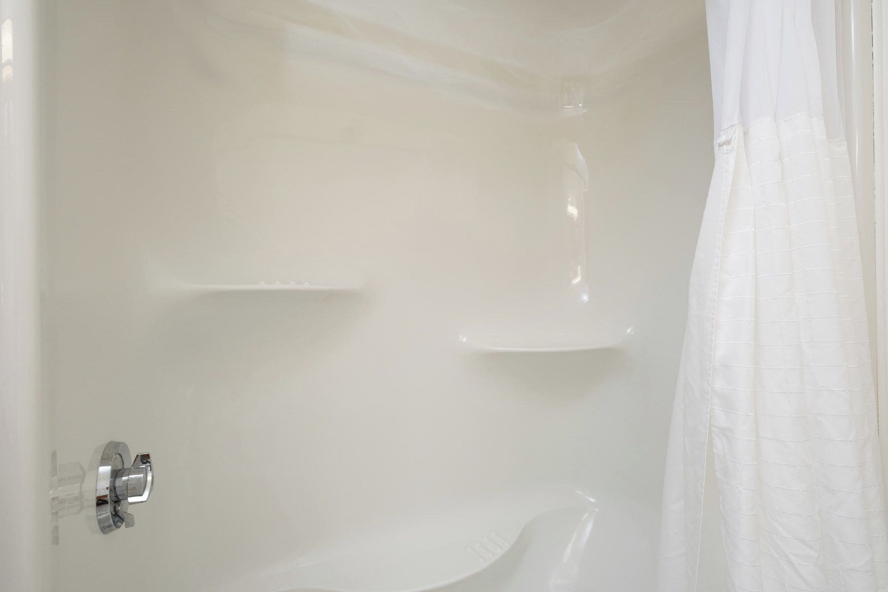 A bathroom with a white shower, a glass shower door, and a white bathtub.