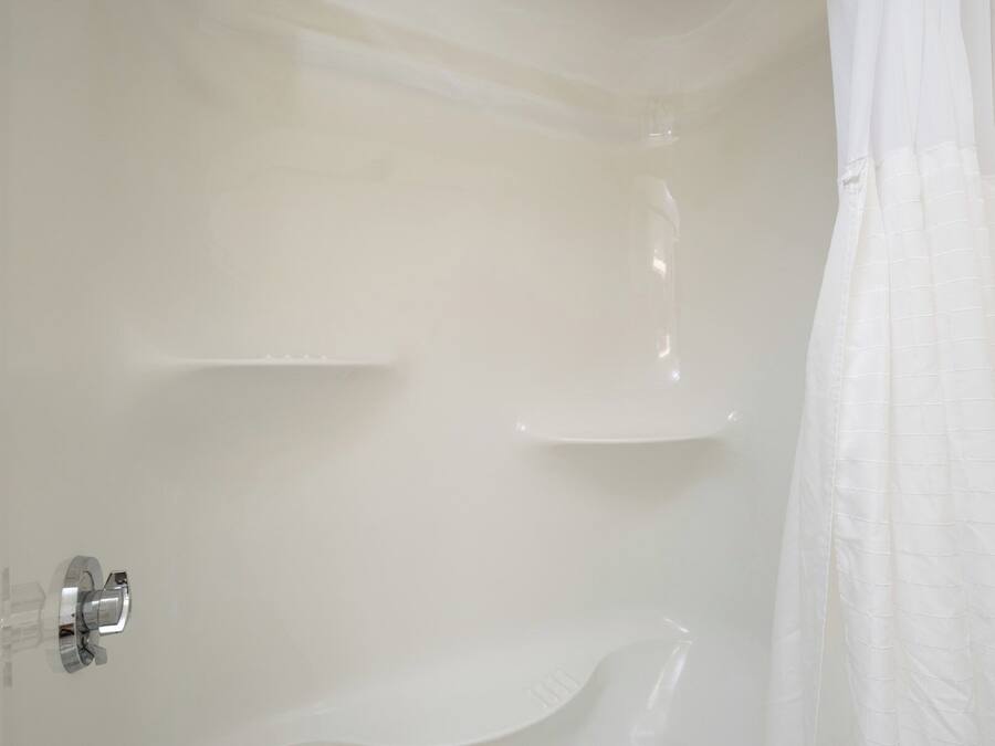 Un bagno con doccia bianca, porta doccia in vetro e vasca da bagno bianca.