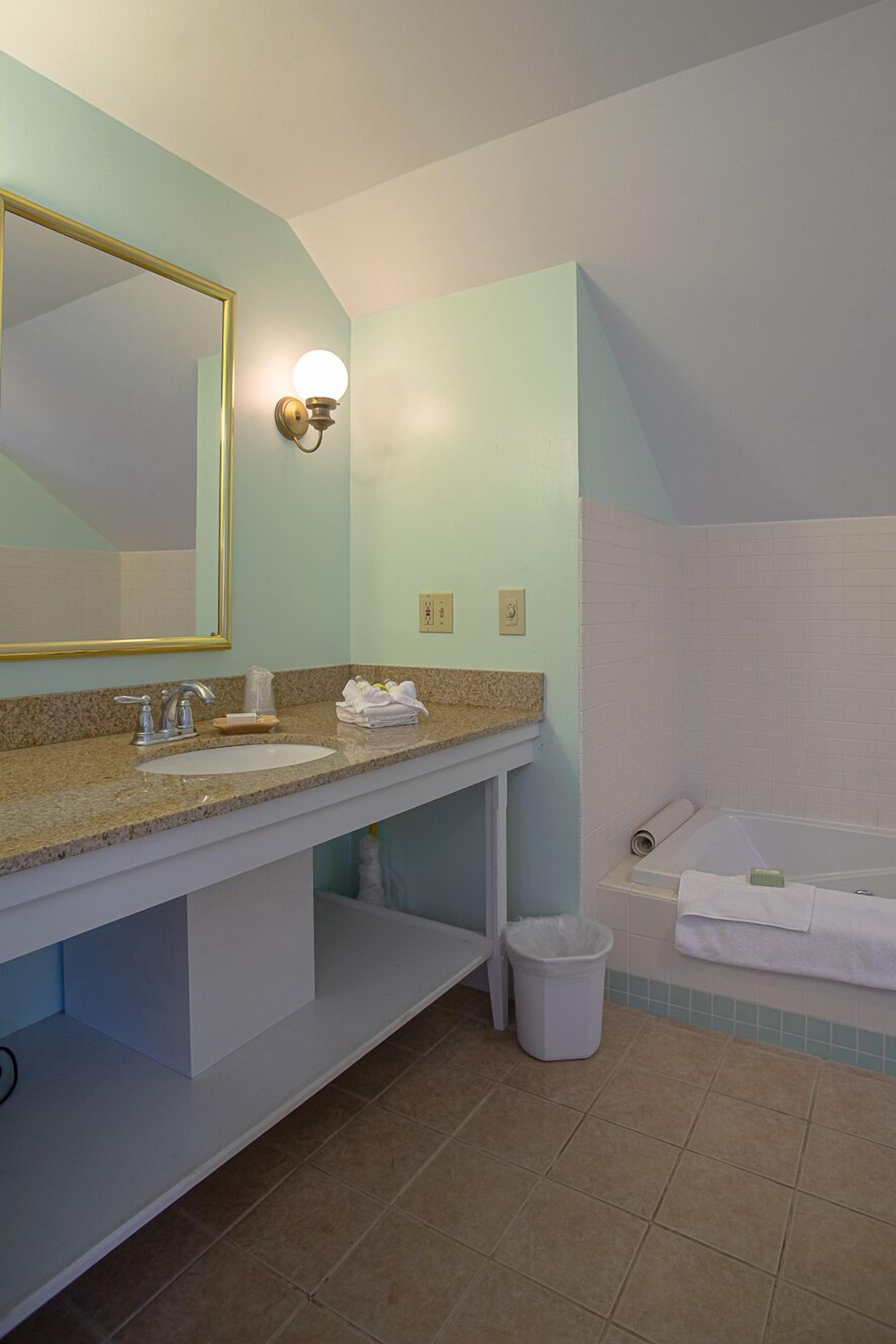 A bathroom with a sink, mirror, and bathtub.