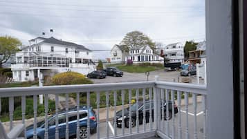 A residential street with houses, parked cars, and a white fence.
