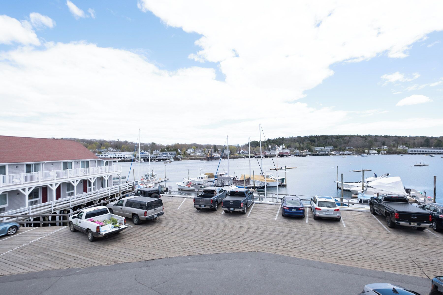 A marina with docked boats, a building with a red roof, and a view of the water.
