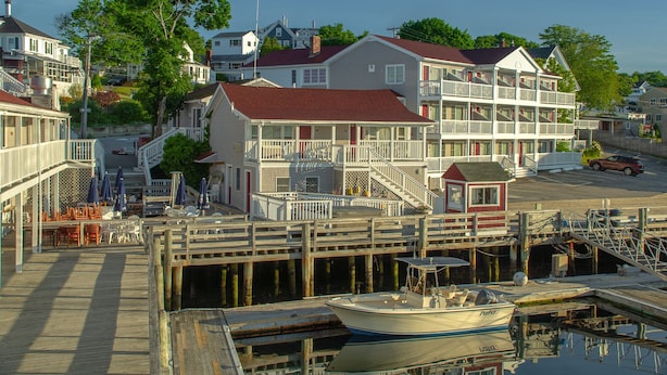 A waterfront property with a dock, a boat, and a multi-story building with balconies. - Tugboat Inn (Boothbay Harbor)