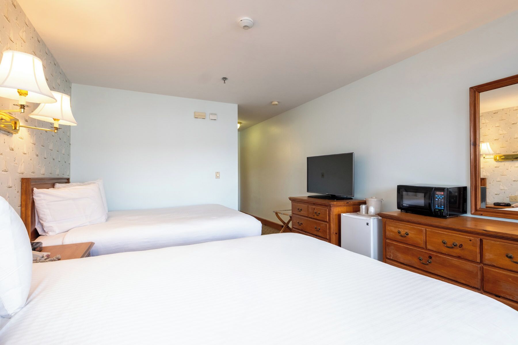 A hotel room with two beds, a television, a microwave, and a small refrigerator.