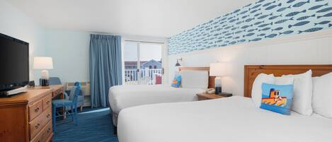A hotel room with two beds, a desk with a TV, a chair, a window with curtains, and a wall with a fish pattern.