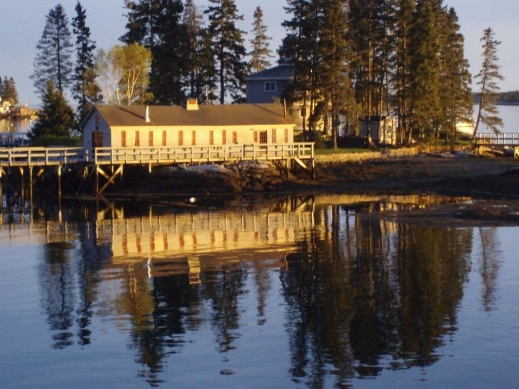 A waterfront building with a dock and reflection in the water.