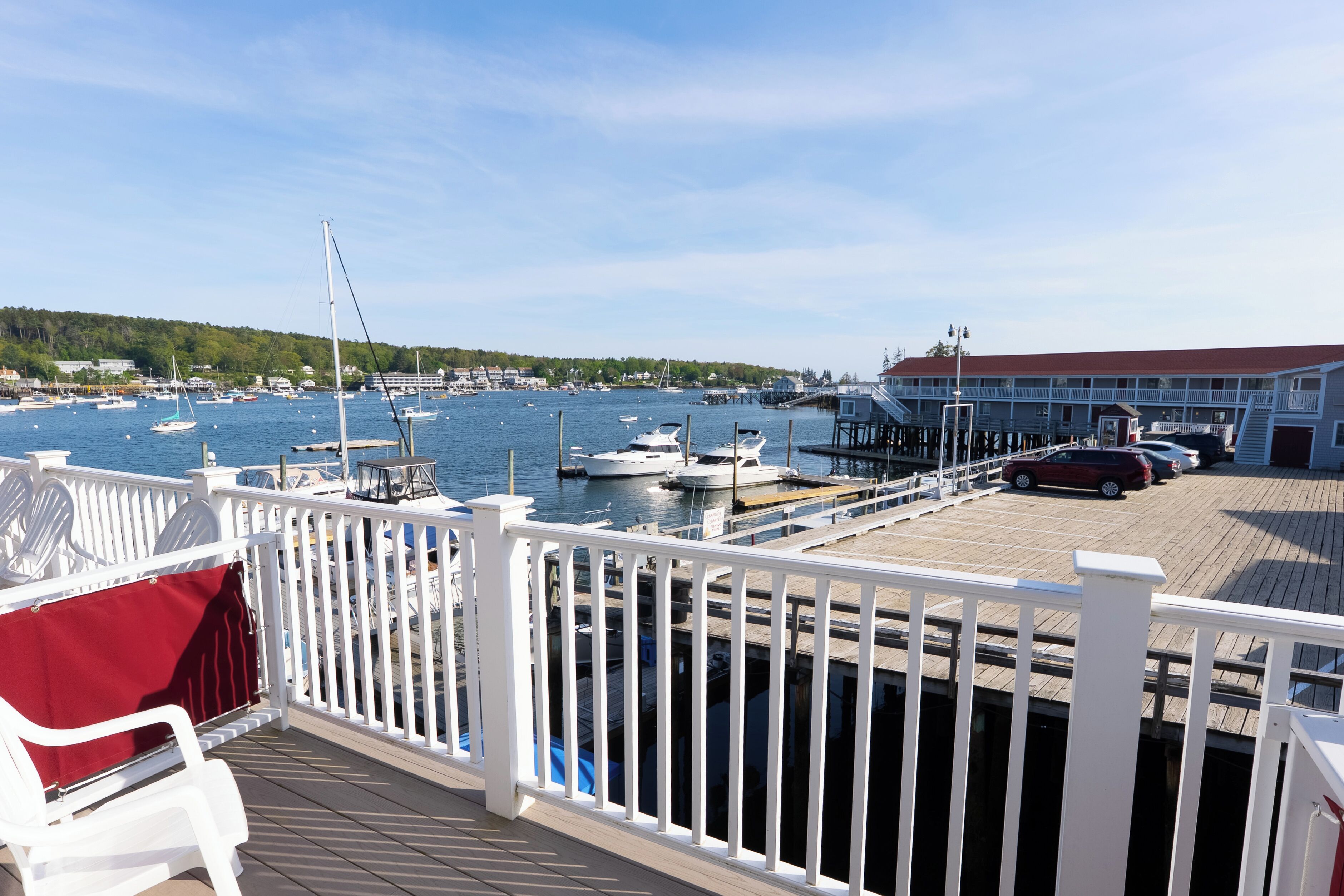 A marina with boats docked, a wooden pier, and a building with a red roof.