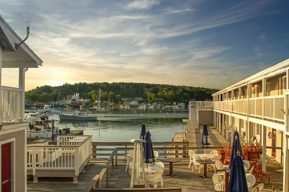 A waterfront hotel with a deck area featuring outdoor seating and a view of the water.