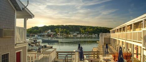 A waterfront hotel with a deck area featuring outdoor seating and a view of the water.