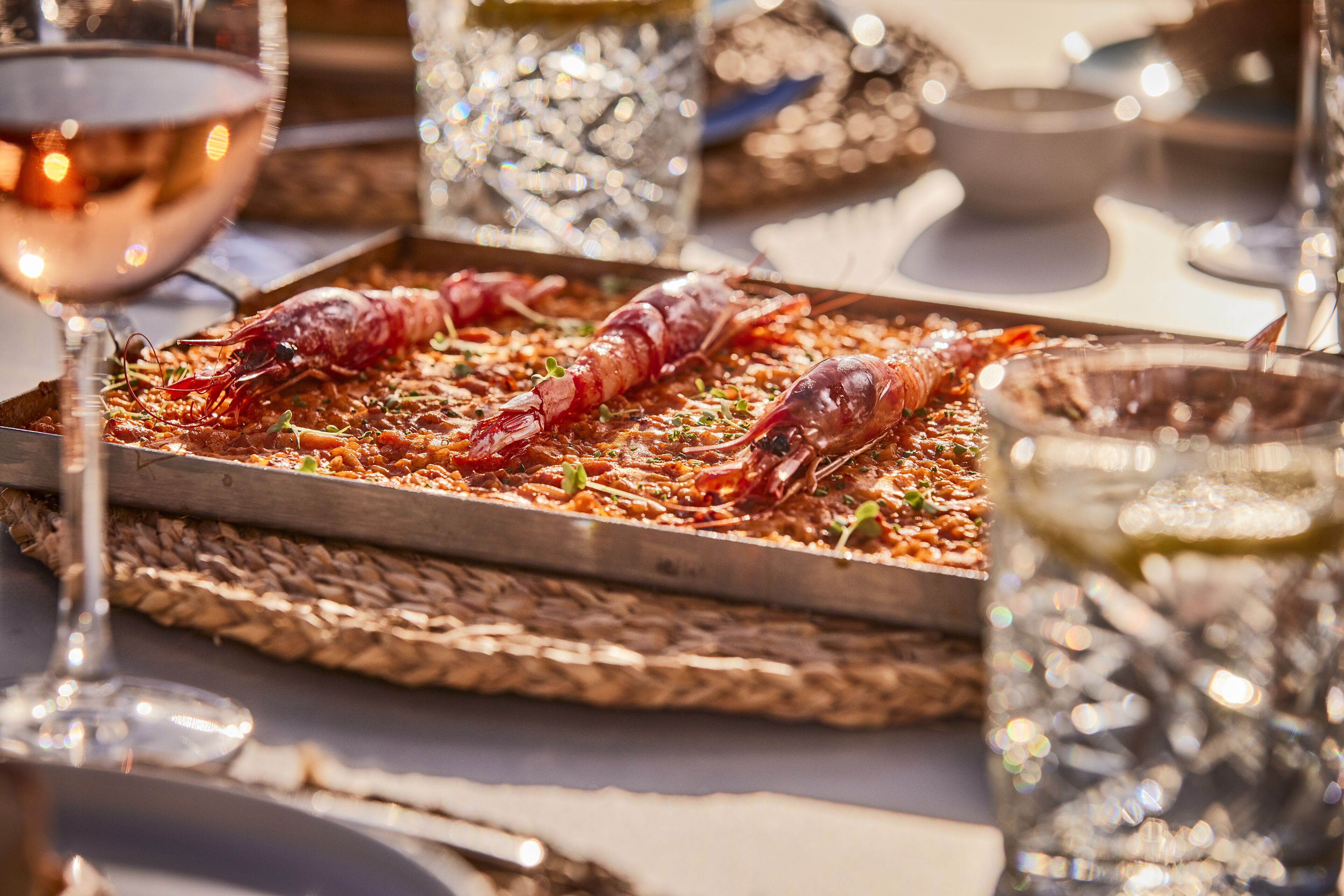 A dining table with a seafood dish, glasses of wine, and decorative glassware.