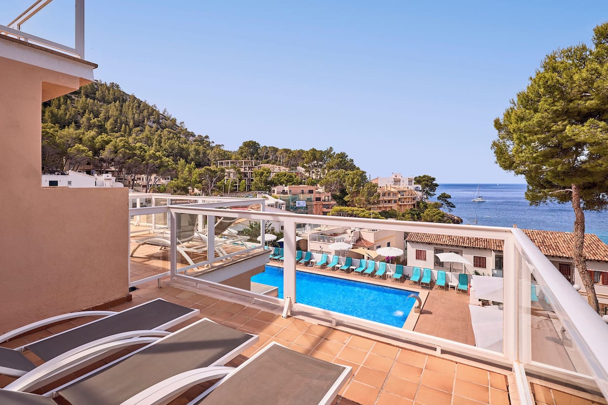 A rooftop pool area with lounge chairs and a view of the sea.