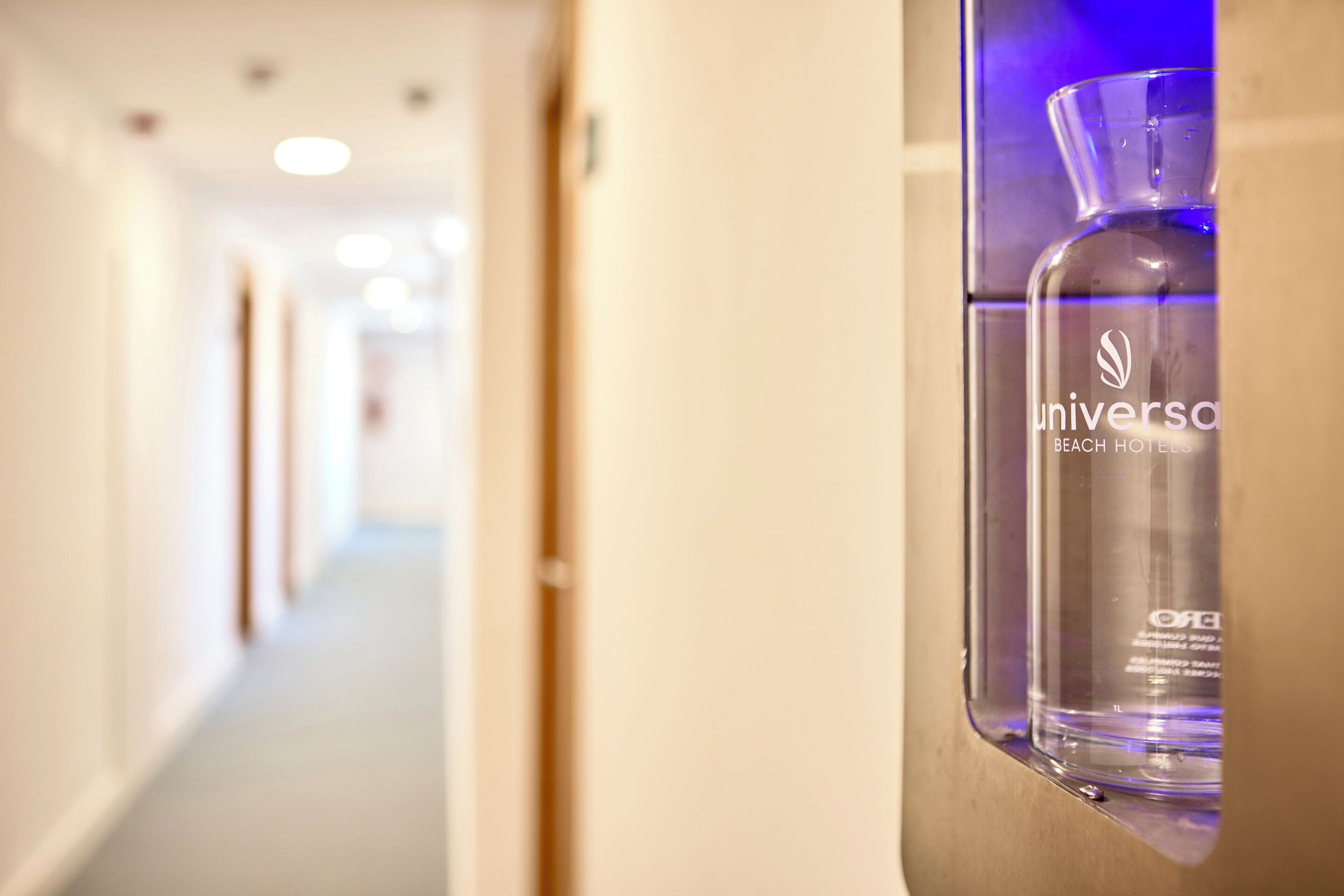 Een hal met een glazen fles met de tekst 'universal beach hotel' op een muur.