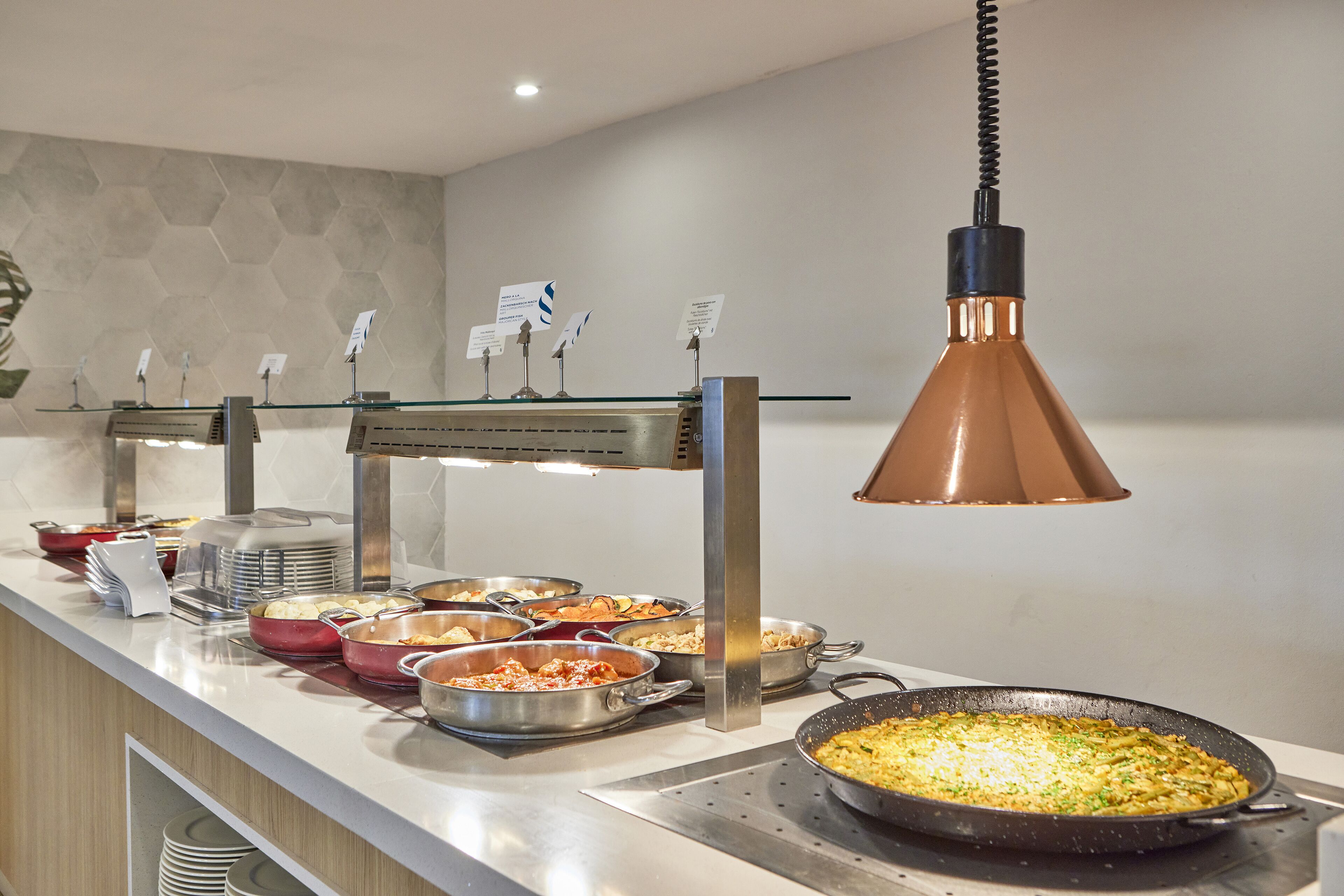 A buffet setup with various dishes and a large pan on a stove.