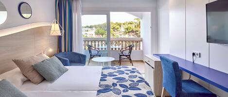 Ein modernes Hotelzimmer mit Bett, Schreibtisch, Stuhl und einem Balkon mit Blick auf die Stadt.