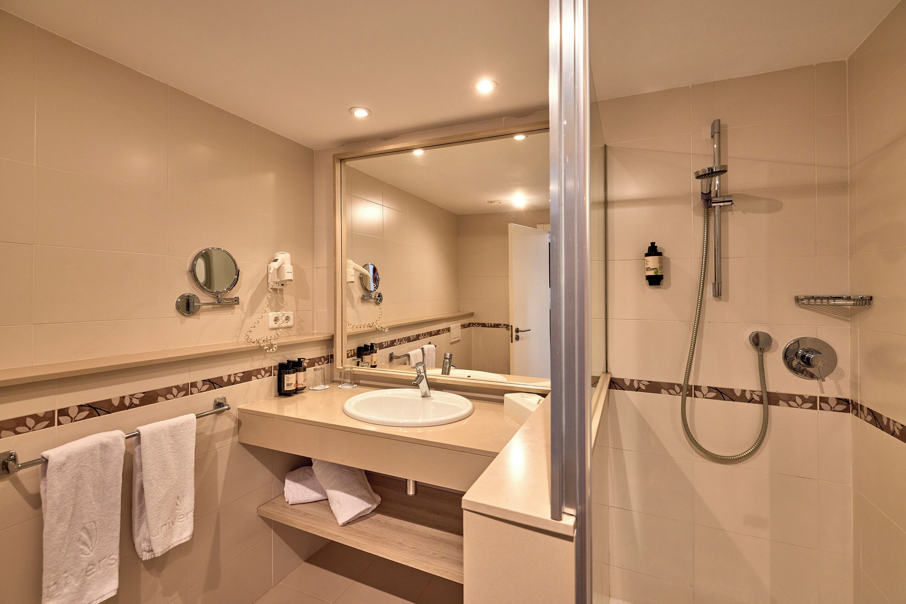 A modern bathroom with a sink, mirror, and shower.