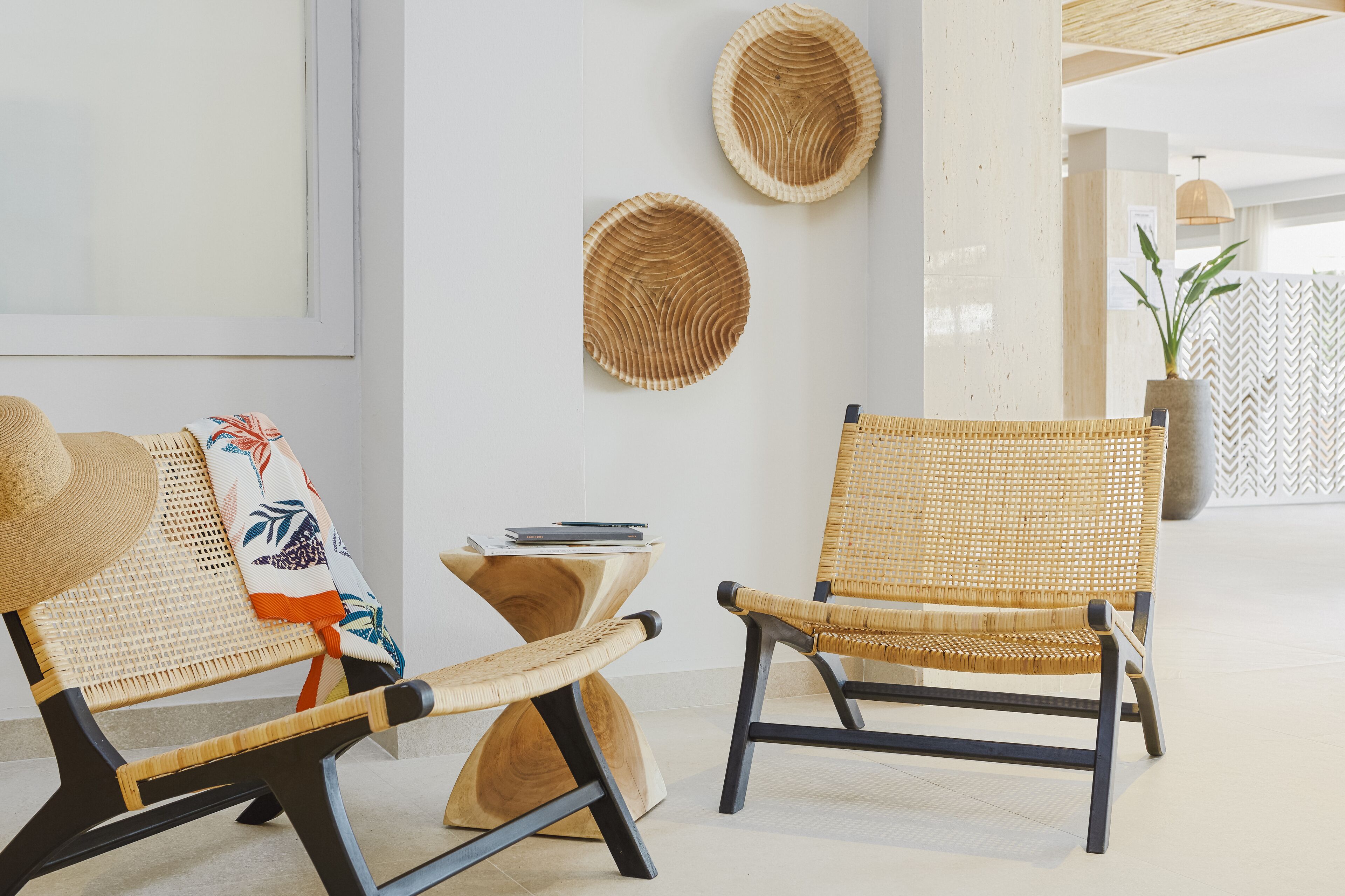 Two wicker chairs with a woven seat and backrest, a small wooden side table, and a framed picture on the wall.