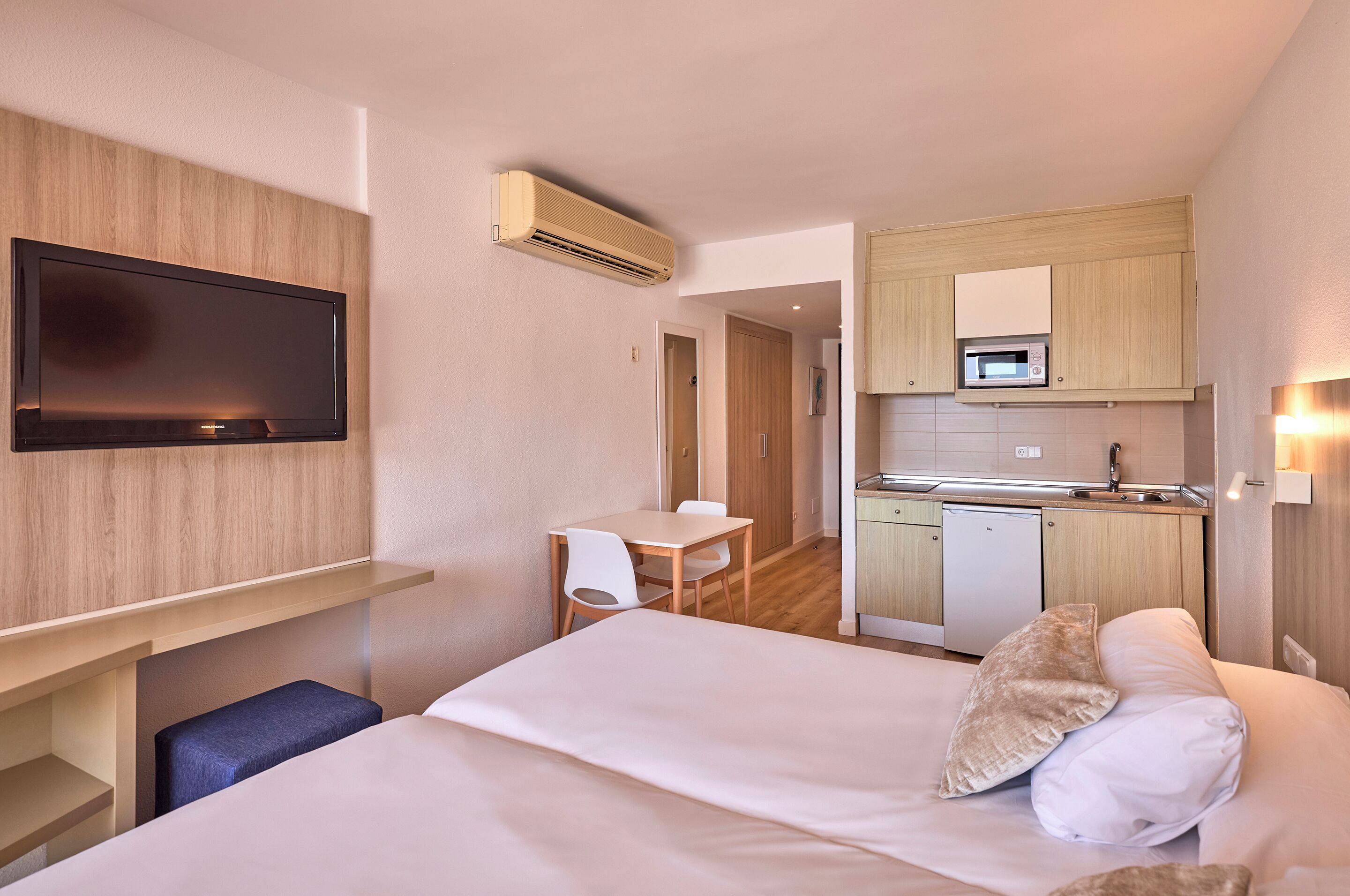 Ein Hotelzimmer mit Bett, Schreibtisch, Stuhl, Fernseher, Mikrowelle und einer kleinen Küchenzeile.
