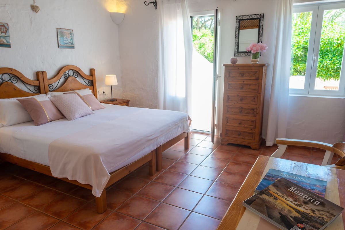 A bedroom with a wooden bed, a nightstand, a dresser, and a table with a book.