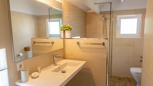 A modern bathroom with a glass shower enclosure, a white sink with a mirror above it, and a toilet.