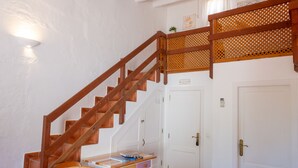 A staircase with wooden railings leading to a landing with a small table and chairs.