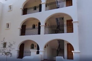 Un edificio de varios pisos con paredes blancas y múltiples balcones.