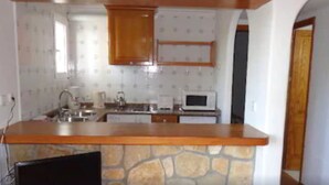 A kitchen with a stone countertop, wooden cabinets, a microwave, and a sink. - Benet Los Pinares Apartments (Santa Eulalia del Rio)