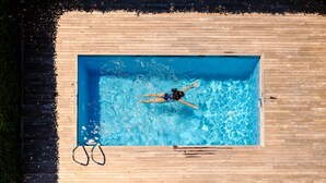 Una piscina rectangular rodeada por una terraza de madera.