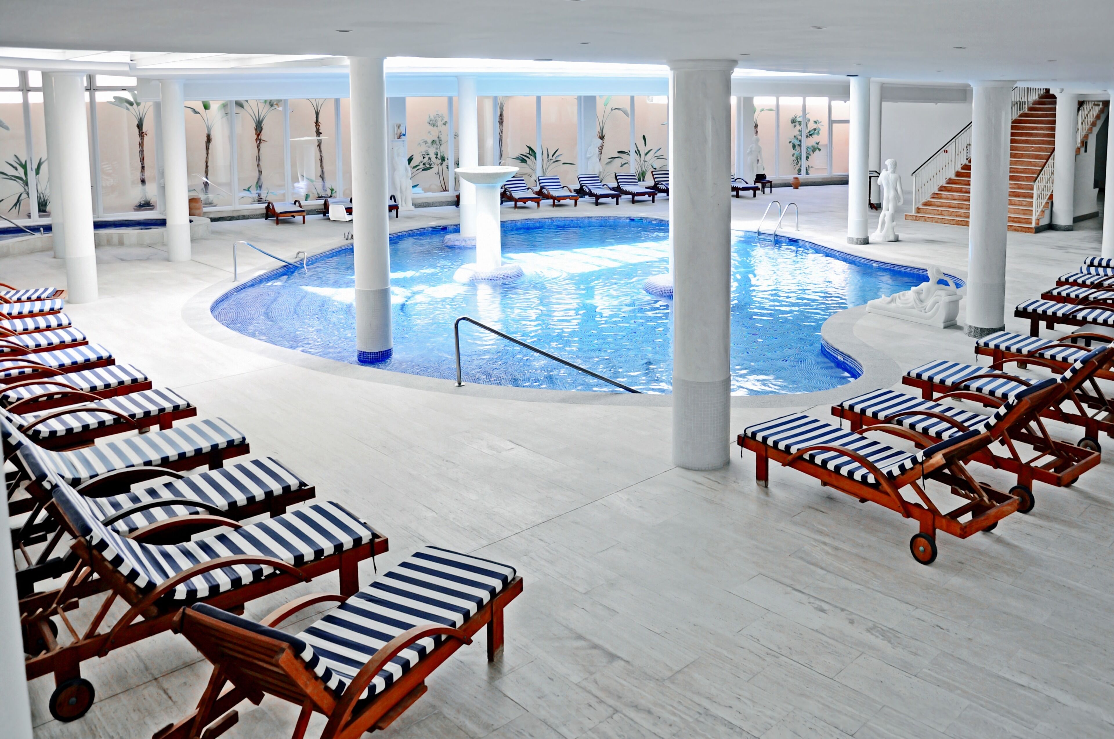 A pool area with lounge chairs, a central pool, and a staircase.