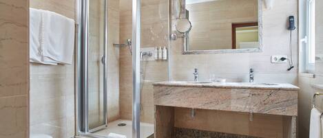 A modern bathroom with a glass-enclosed shower, a marble sink, and a large mirror.